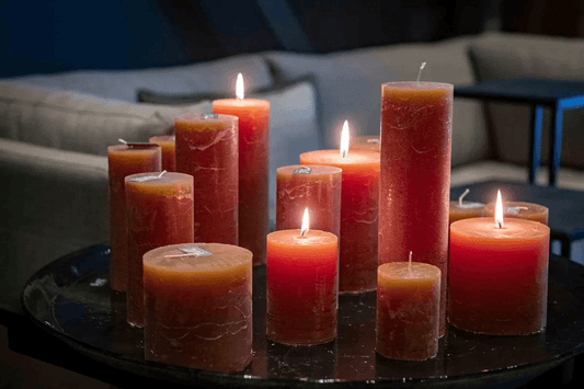 Hand poured candles in various sizes and shades of red displayed on a black tray in a cozy living room