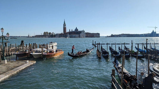 Scenic view of gondolas on Venetian lagoon with historic buildings representing murano glass heritage