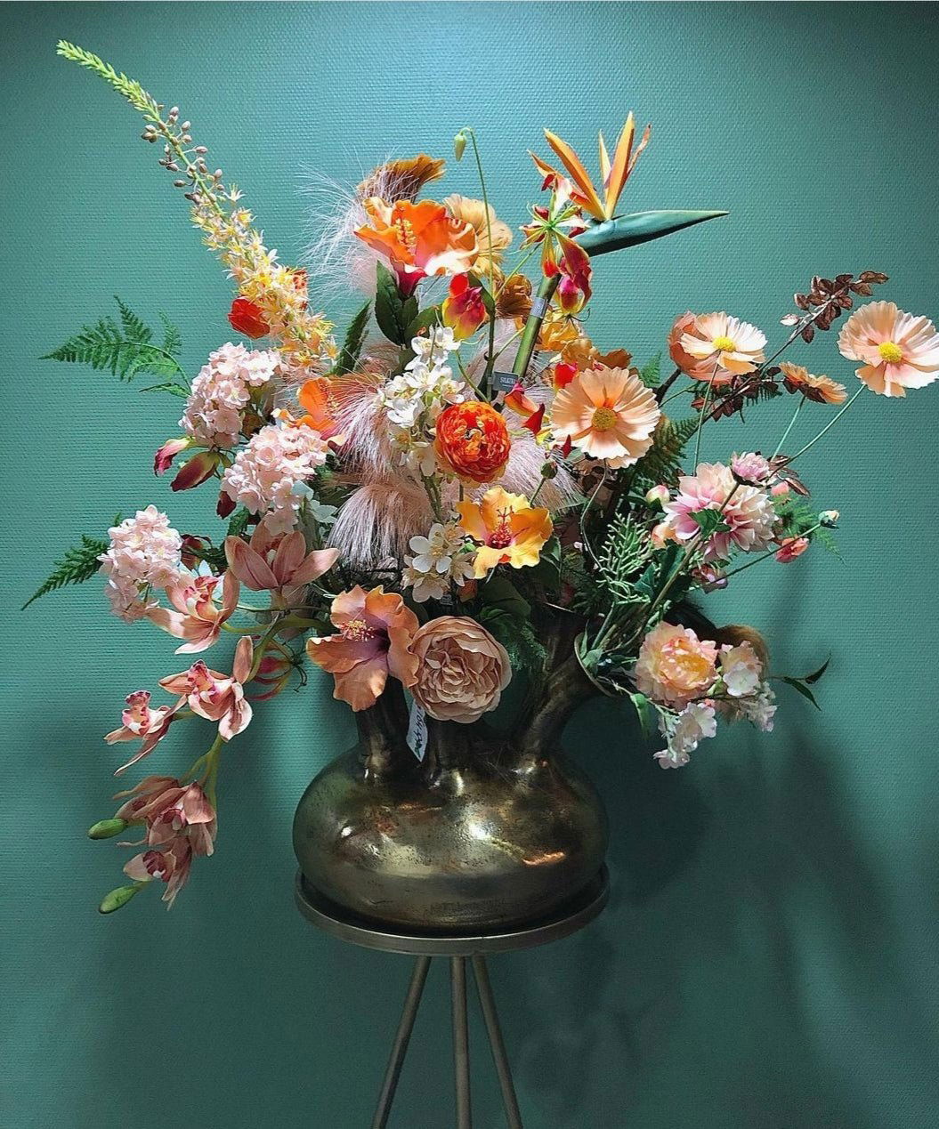 Lowlands Design vase bronze with a unique rounded shape holding vibrant mixed flowers on a stand