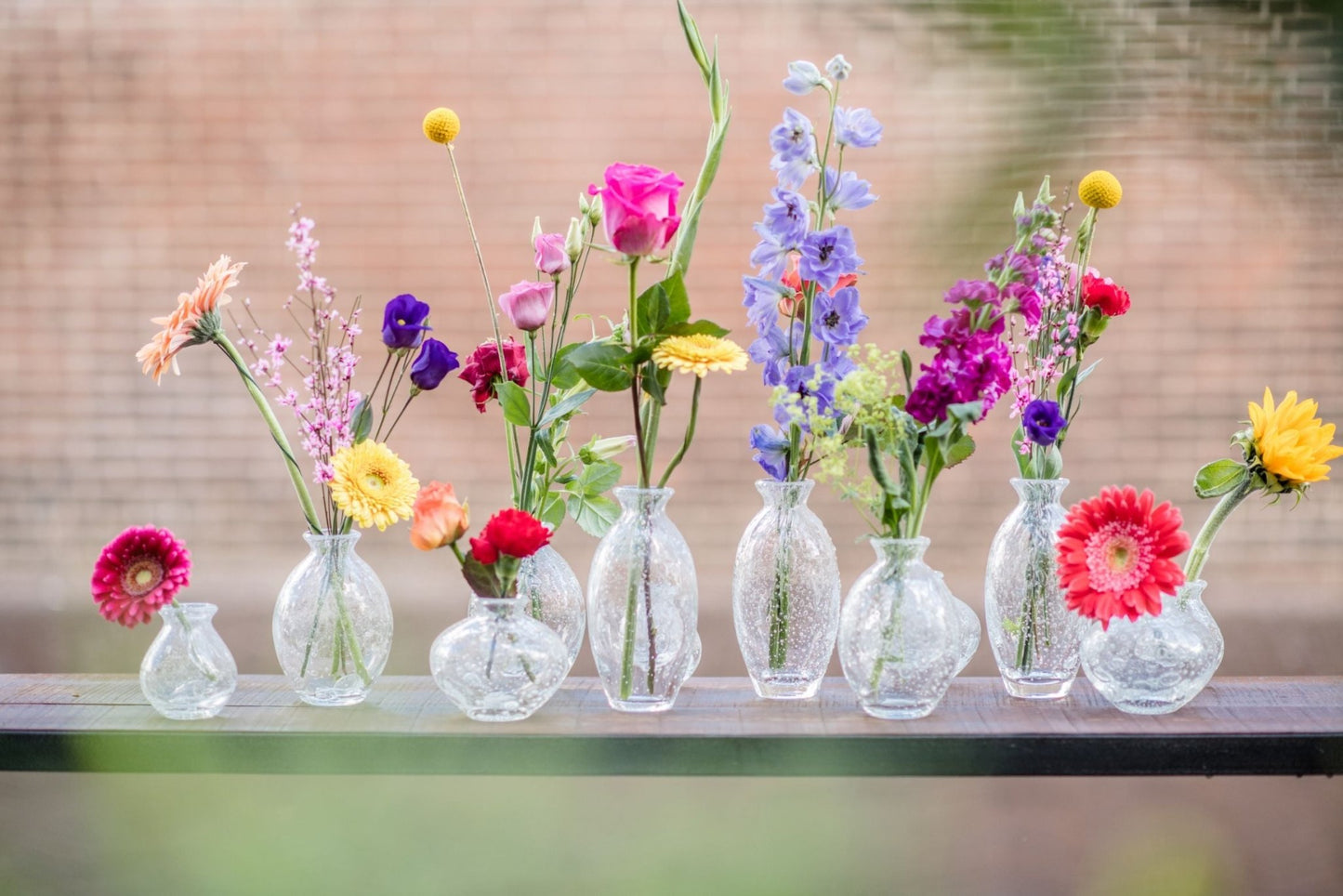 Lowlands Design vase set with clear textured glass holding colorful fresh flowers on a wooden ledge