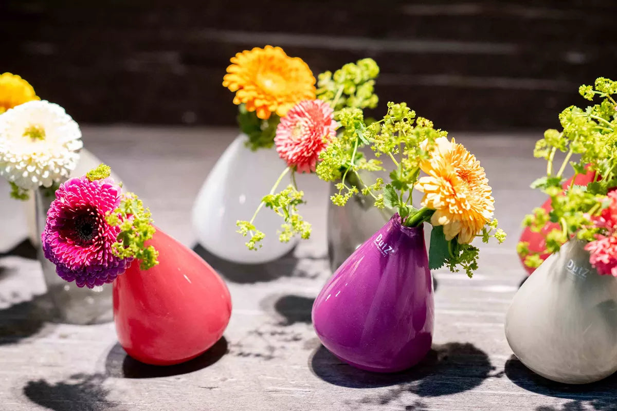Colourful Lowlands Design tumbling vase with fresh flowers on wooden surface in bright setting