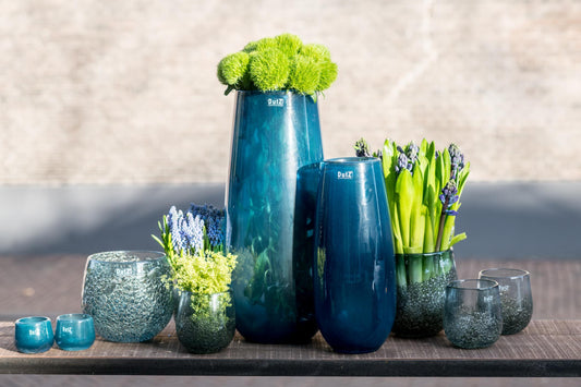Collection of Lowlands Design glass flower vases in various sizes and shapes, featuring vibrant flowers