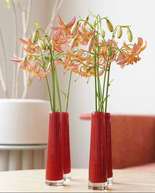 Lowlands Design red solifleur budvase holding delicate orange lilies on wooden table
