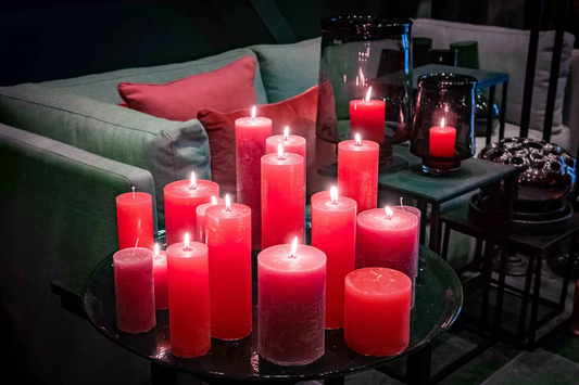 Assorted red candles by Lowlands Design burning on a black round table in a cosy living room
