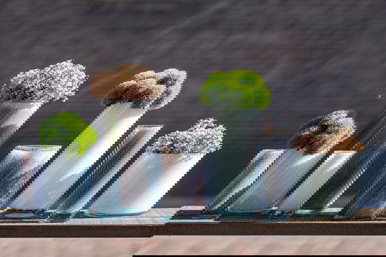 Set of Lowlands Design cylinder vase collection with various sizes holding green and white floral arrangements