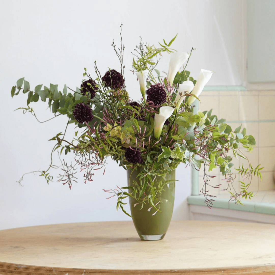 Lowlands Design green flowervase with mixed white and dark purple flowers on wooden table