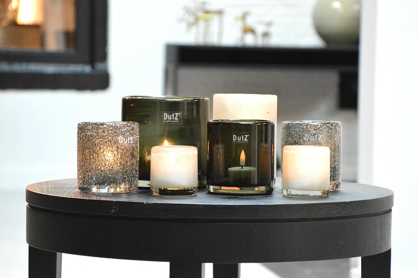Glass cylinder candleholder smoke in various sizes displaying lit candles on a black table