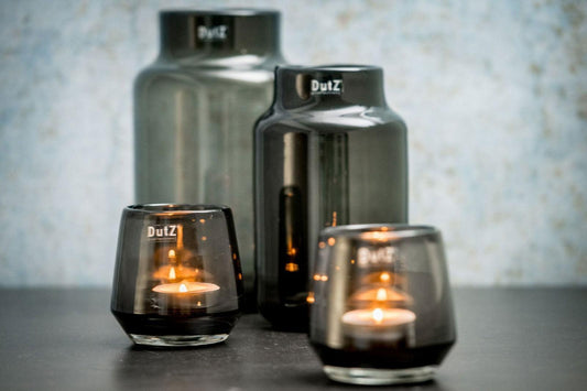 Lowlands Design barrel-shaped vase set in smoky glass with lit candles inside for decorative use