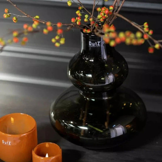 Lowlands Design black glass vase with decorative orange berry branches on dark surface