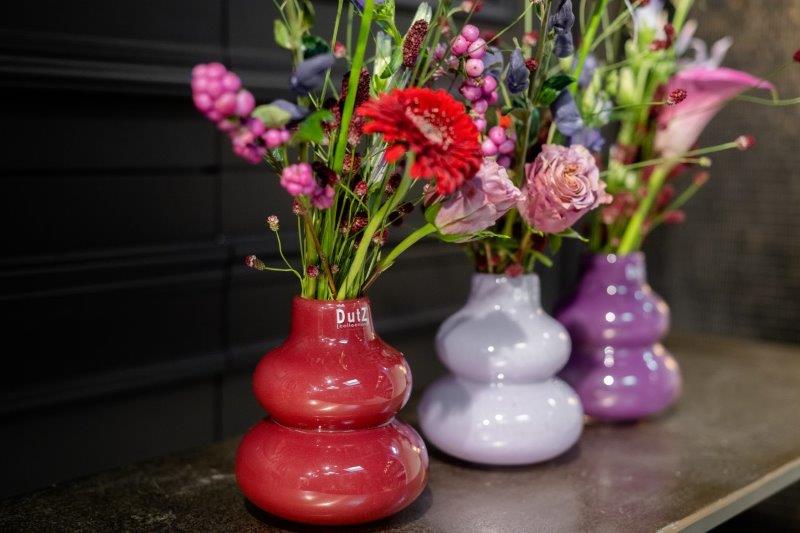 Lowlands Design display of three small bulbous glass vases in red lilac and purple with flowers handmade dutz vase
