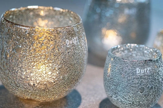 Lowlands Design silver textured hurricane candleholder with lit candle creating warm ambient light