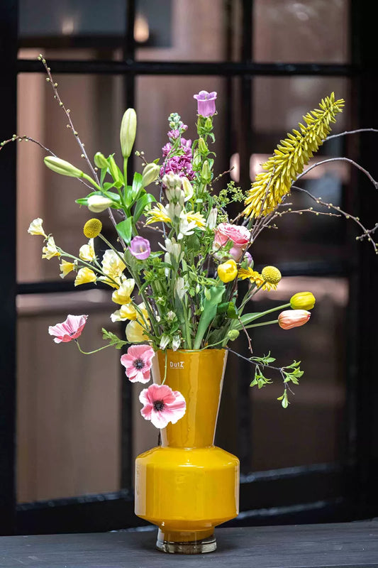 Lowlands Design ochre yellow vase with mixed spring flowers arrangement on a dark window ledge