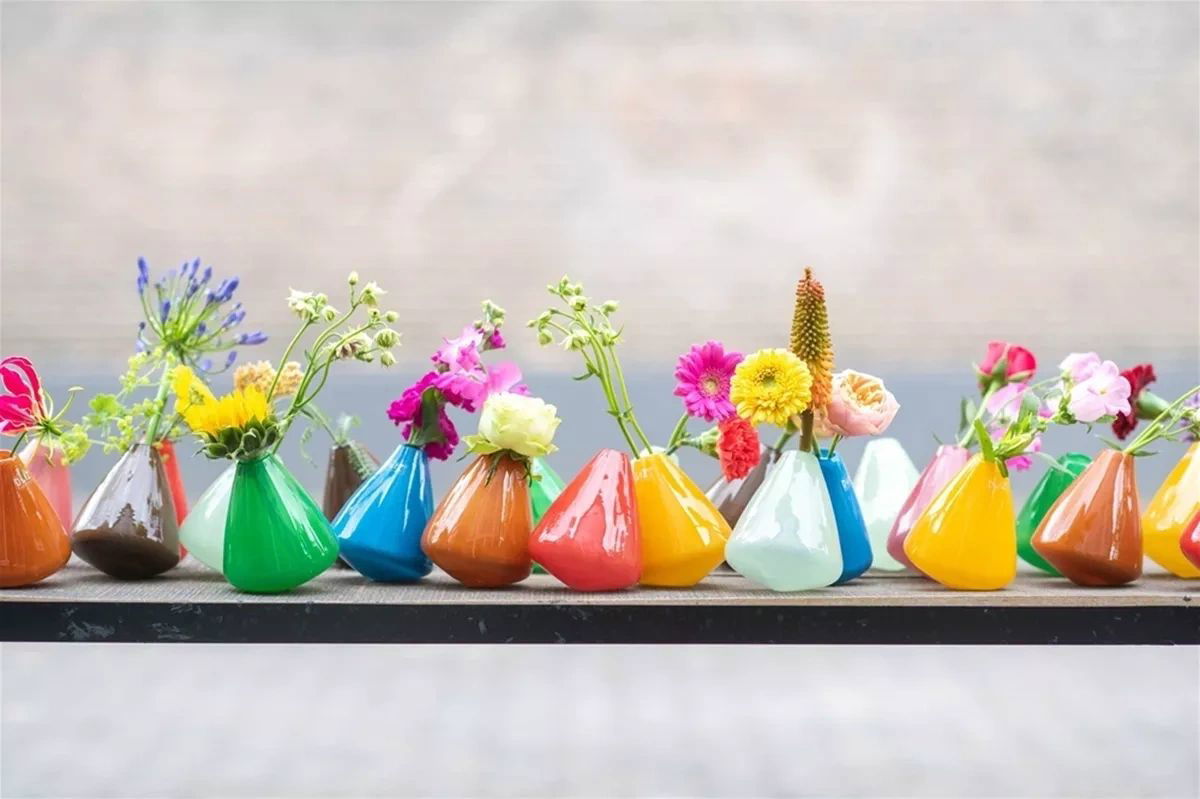 Colourful tumbling vase collection by Lowlands Design with various fresh flowers on display