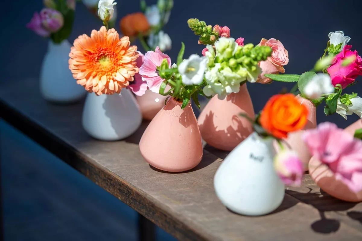 Lowlands Design tumbling vase collection in pastel colours holding vibrant fresh flowers on wooden table