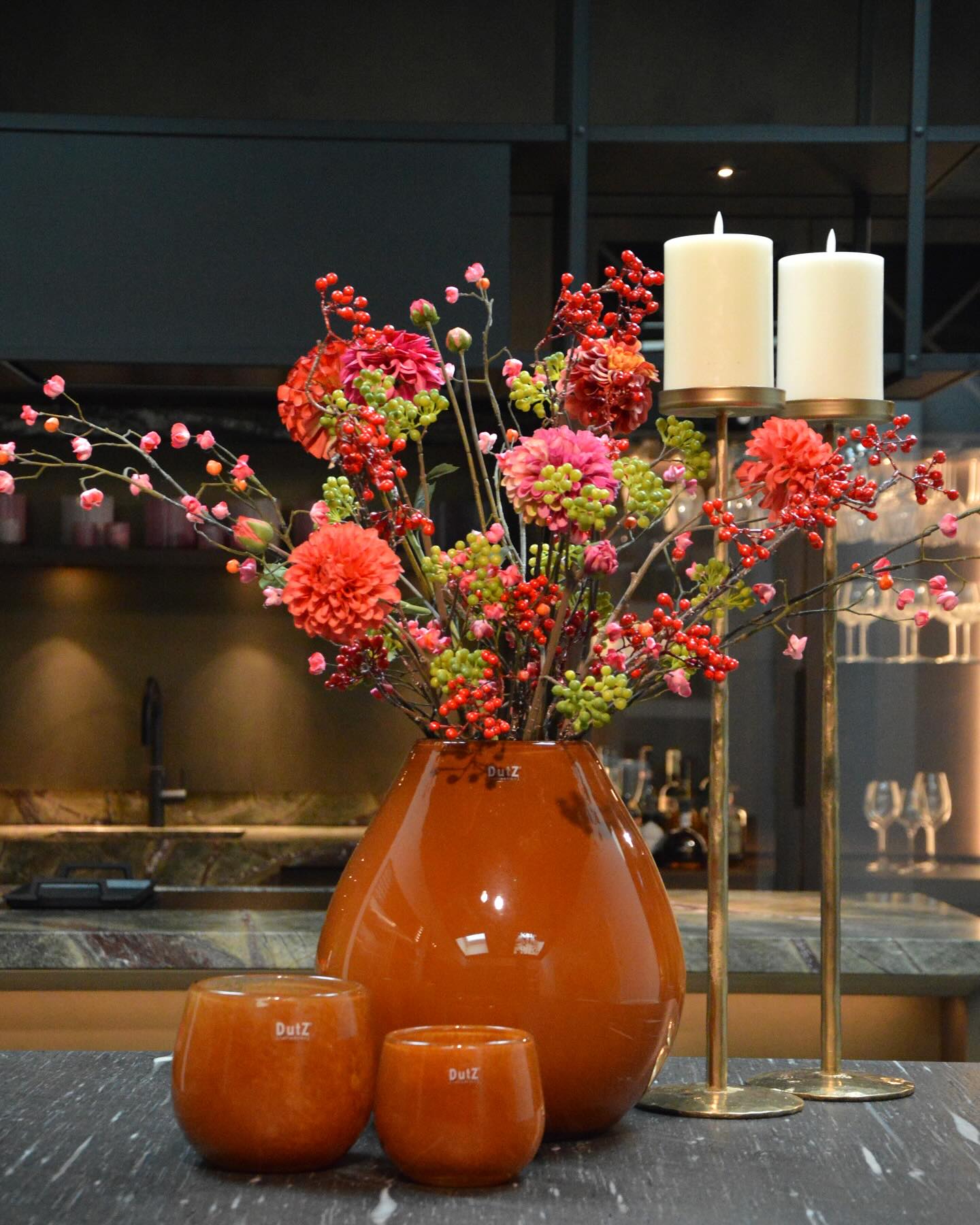 Lowlands Design orange glazed vase with vibrant floral arrangement displayed on kitchen counter
