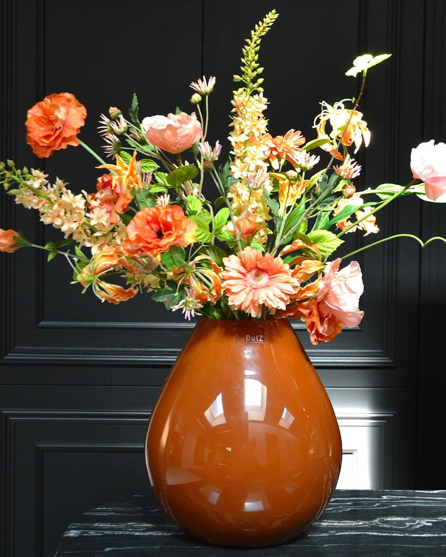 Lowlands Design brown glossy vase with vibrant orange and pink flowers on black marble surface