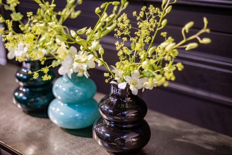 Lowlands Design black and blue ceramic vase with green and white floral arrangement on table