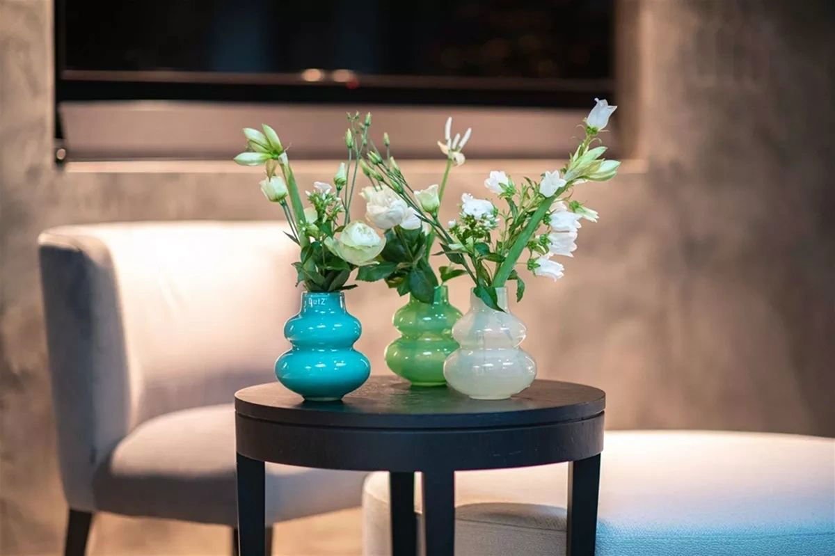 Three colourful Lowlands Design vases on a black round table with white flowers in a modern living room