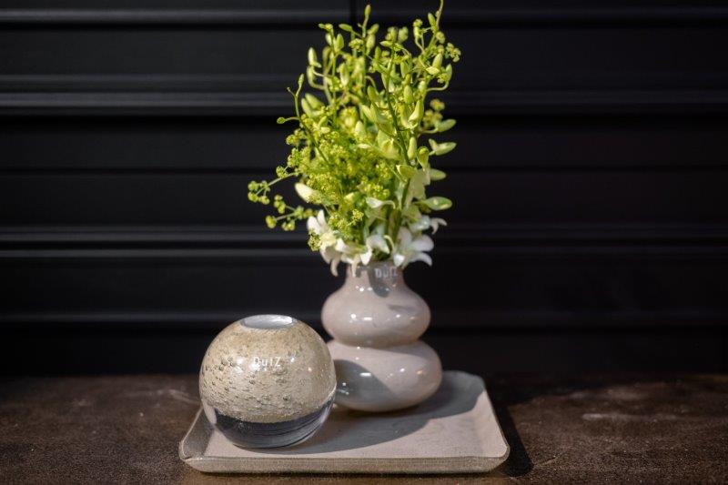 Lowlands Design ceramic vase with a unique twisted shape holding green and white flowers on a tray