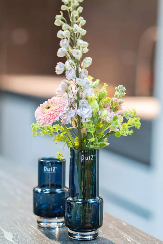 Lowlands Design dark blue glass vase holding a colorful fresh flower arrangement on a table