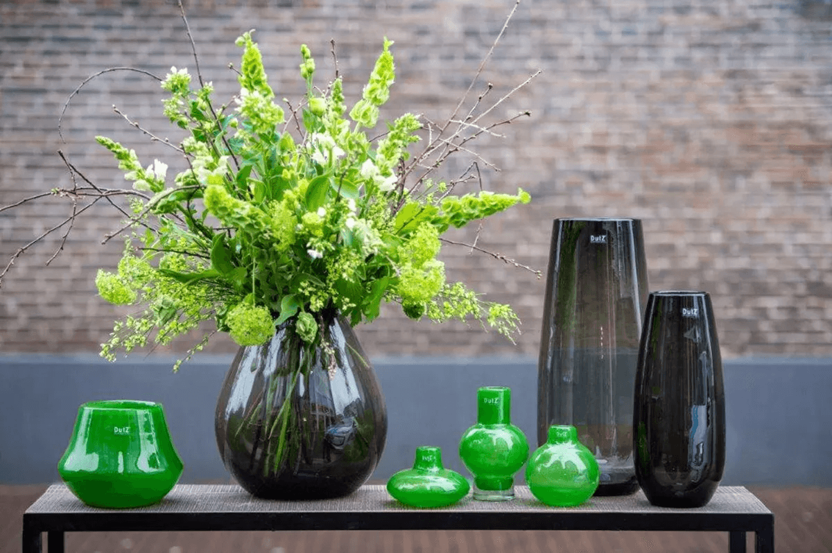 Lowlands Design vase collection featuring green and black modern vases with fresh green flowers on a wooden table