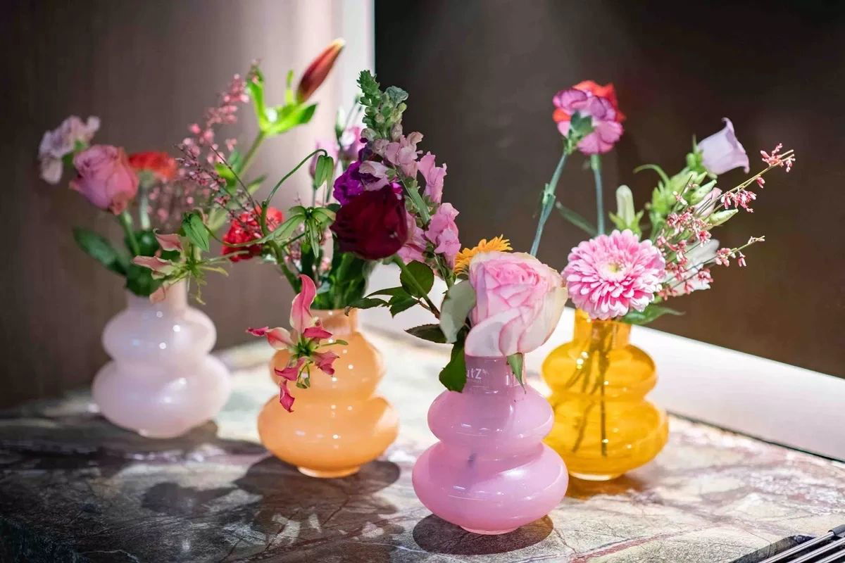 Colourful Lowlands Design glass vase collection with flowers on marble surface