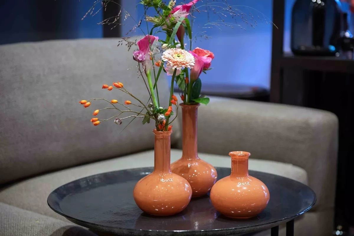 Lowlands Design terracotta vase set with tall and short vases holding fresh flowers on a black round table