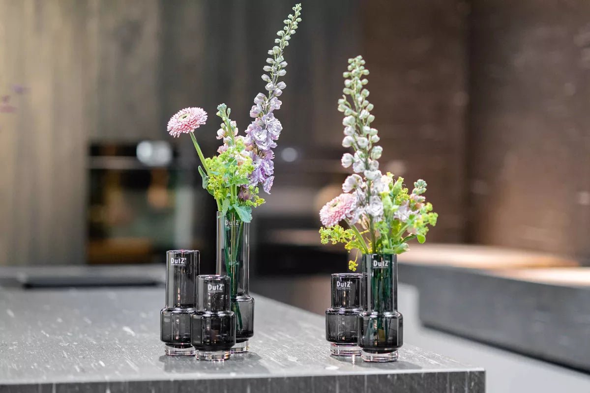 Lowlands Design black glass vase with tall flowers on modern gray marble table