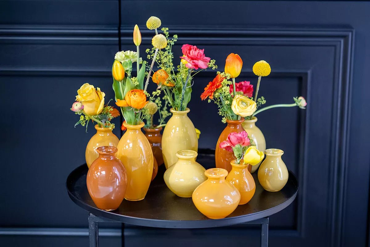 Lowlands Design vase set with various shapes in warm yellow and orange tones filled with colorful fresh flowers