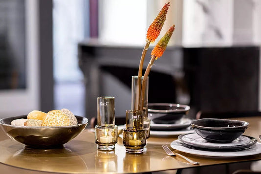 Lowlands Design vase with orange flowers on dining table next to black plates and bowls