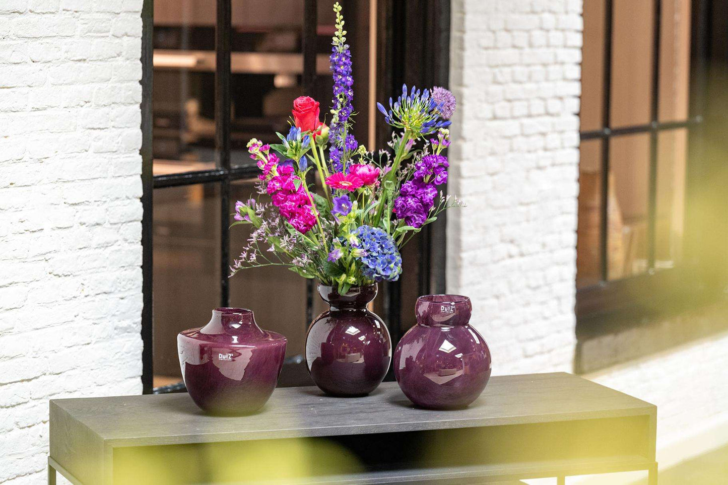 Lowlands Design Glass Posy vase plum with vibrant flowers in a stylish indoor setting