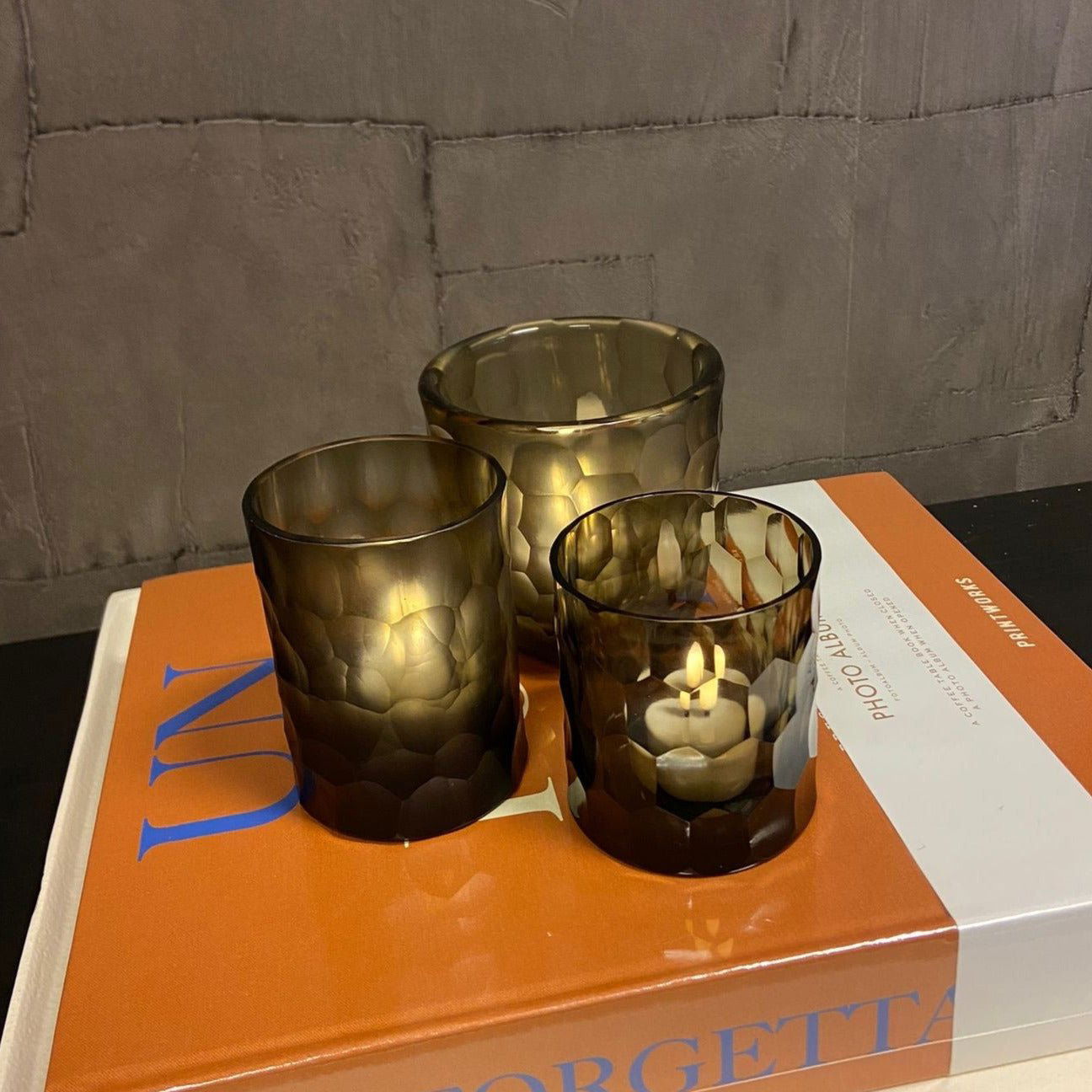 Lowlands Design set of three brown textured glass candleholder on an orange photo album