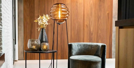 Stylish interior scene featuring a lit DutZ lighting glass lamp with a velvet armchair and decorative table