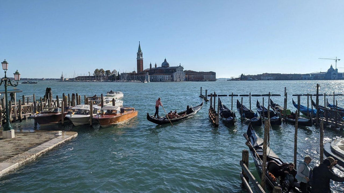 Scenic view of gondolas on Venetian lagoon with historic buildings representing murano glass heritage
