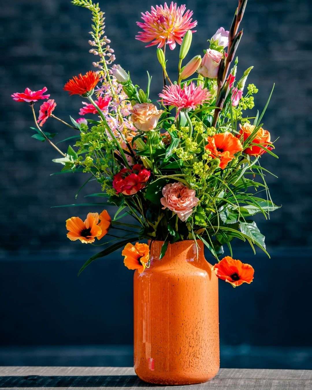 Lowlands Design Apothecary Glass Vase in Orange with Colourful Floral Arrangement
