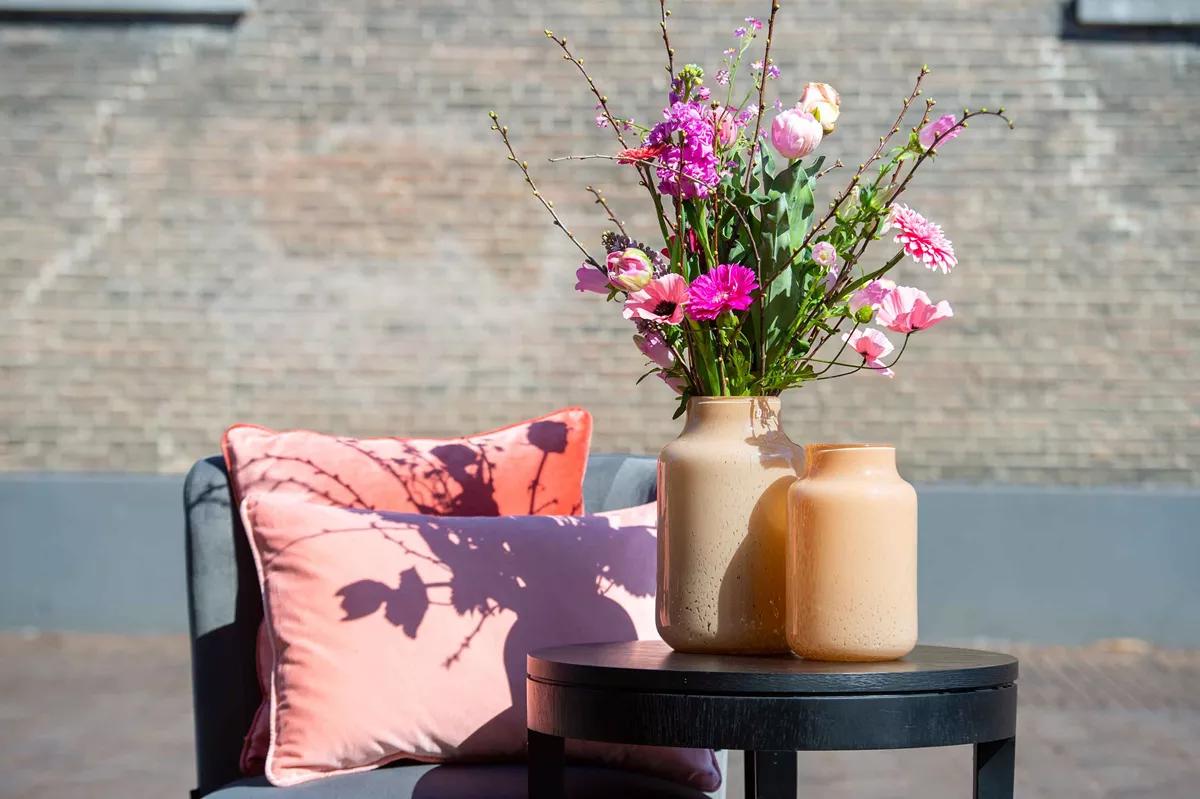 Stylish Apothecary Glass Vase with Flowers on a Table Next to a Pink Cushion