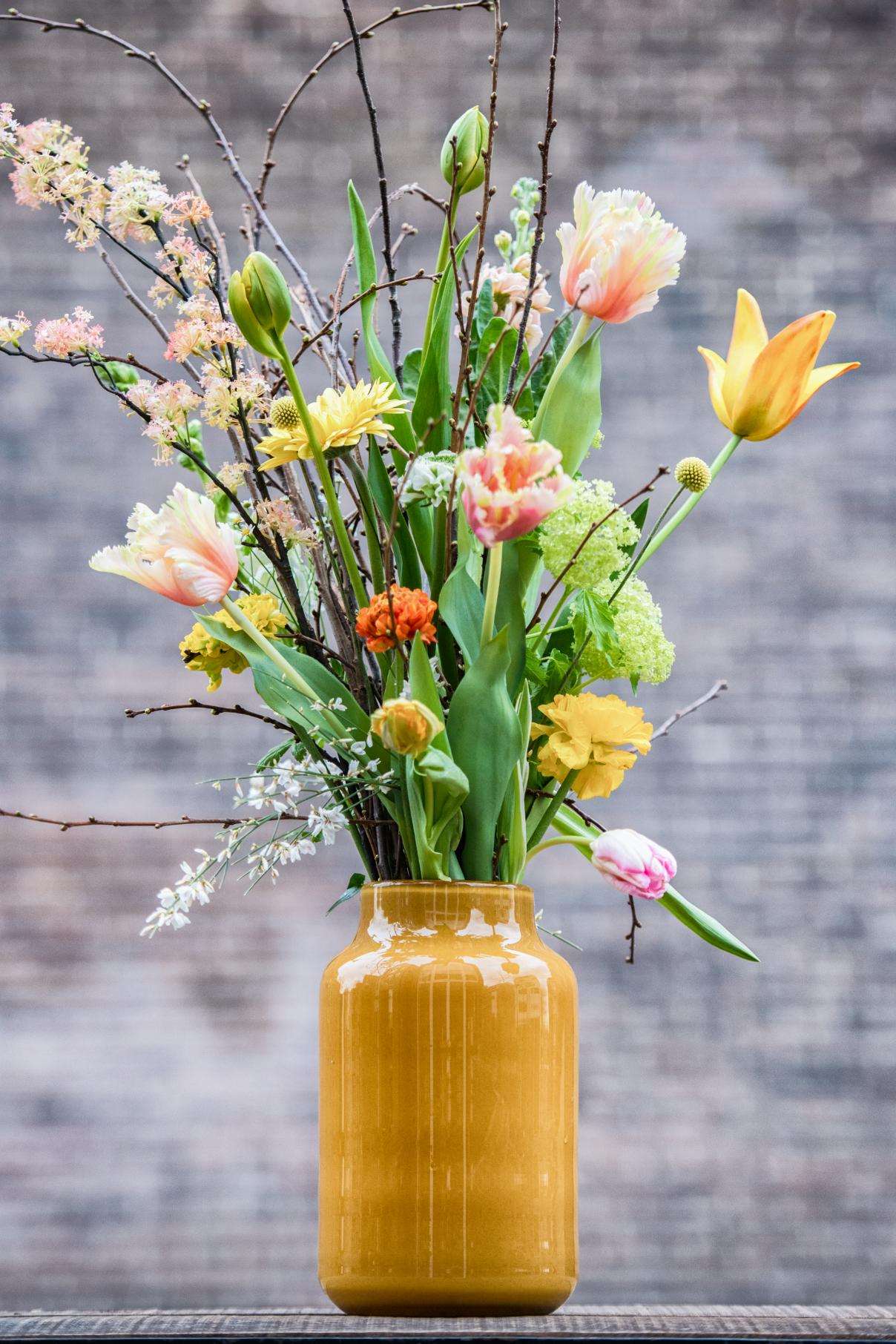 Lowlands Design Apothecary Glass Vase filled with vibrant spring flowers and decorative branches