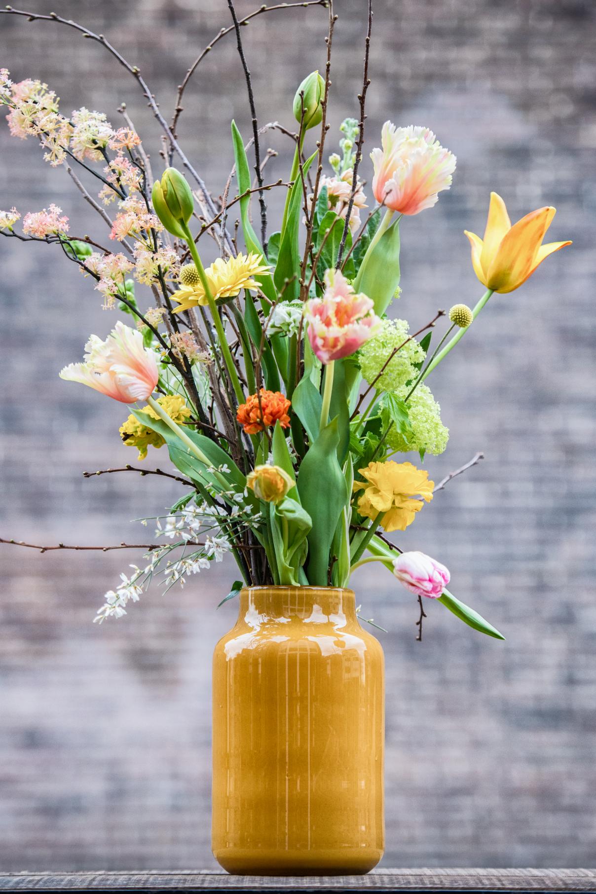 Lowlands Design Apothecary Glass Vase filled with vibrant spring flowers and decorative branches