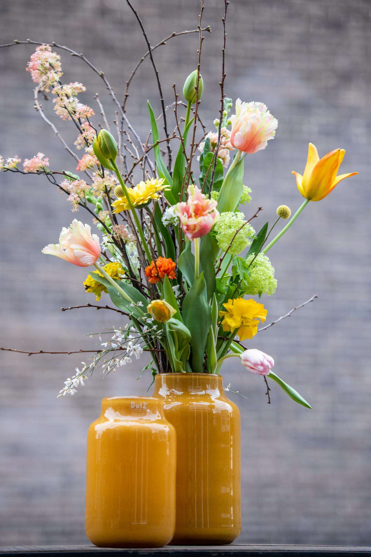 Lowlands Design Apothecary Glass Vase in amber with vibrant flowers and natural greenery