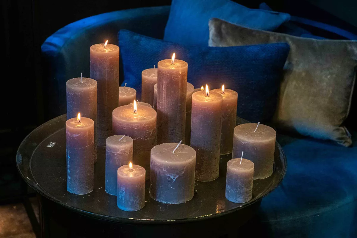 Set of decorative Lowlands Design candles in various sizes, glowing softly on a dark table