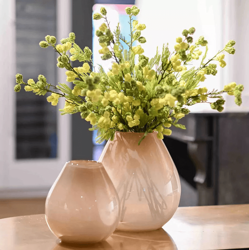 Lowlands Design beige glass vase with green floral arrangement on wooden table
