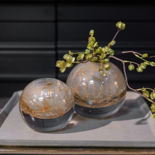 Lowlands Design decorative ball vases with crackled gold and black finish holding greenery on a tray