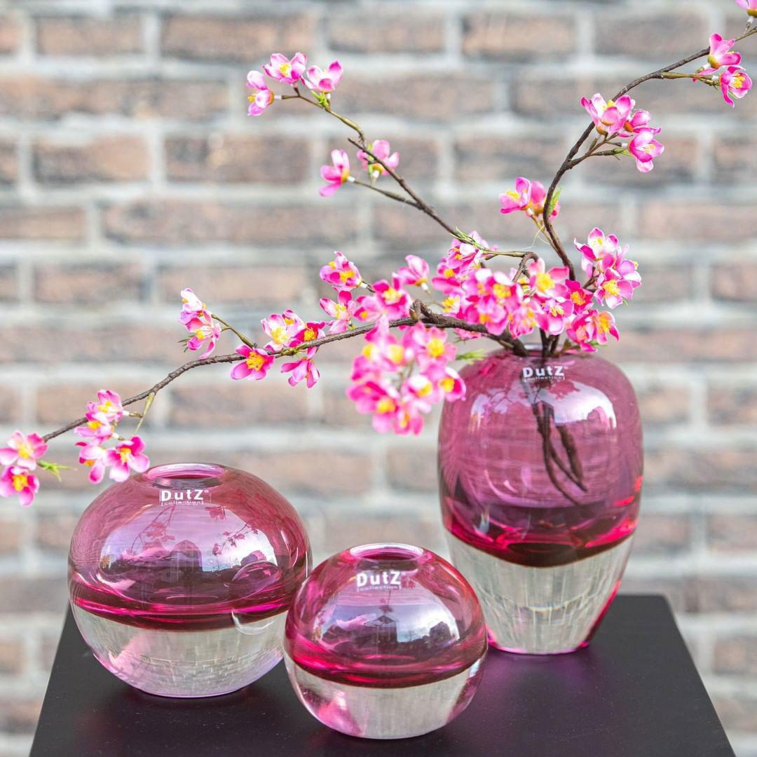 Lowlands Design pink and clear glass ball vase set with blooming pink flowers on black surface