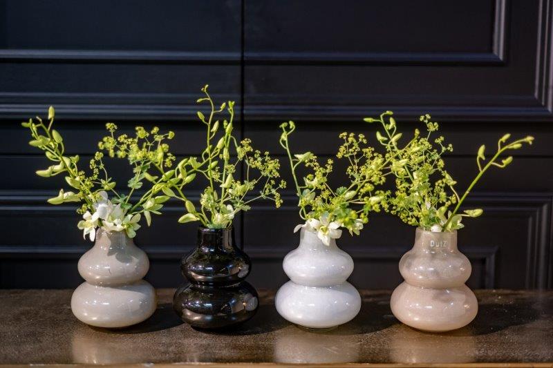 Lowlands Design beige decorative vase displayed with black and white double gourd vases and green floral stems