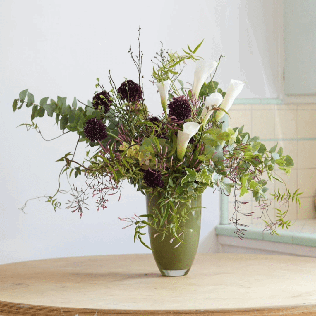Lowlands Design green flowervase with mixed white and dark purple flowers on wooden table