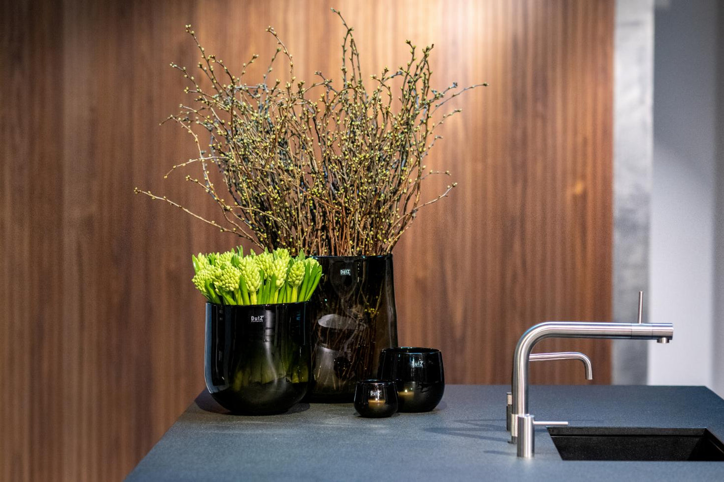 Stylish Lowlands Design glass oval vase displaying branches and greens on a modern kitchen counter