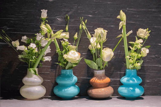 Lowlands Design green glass vase decorative among four bulbous vases in teal brown and cream with white flowers