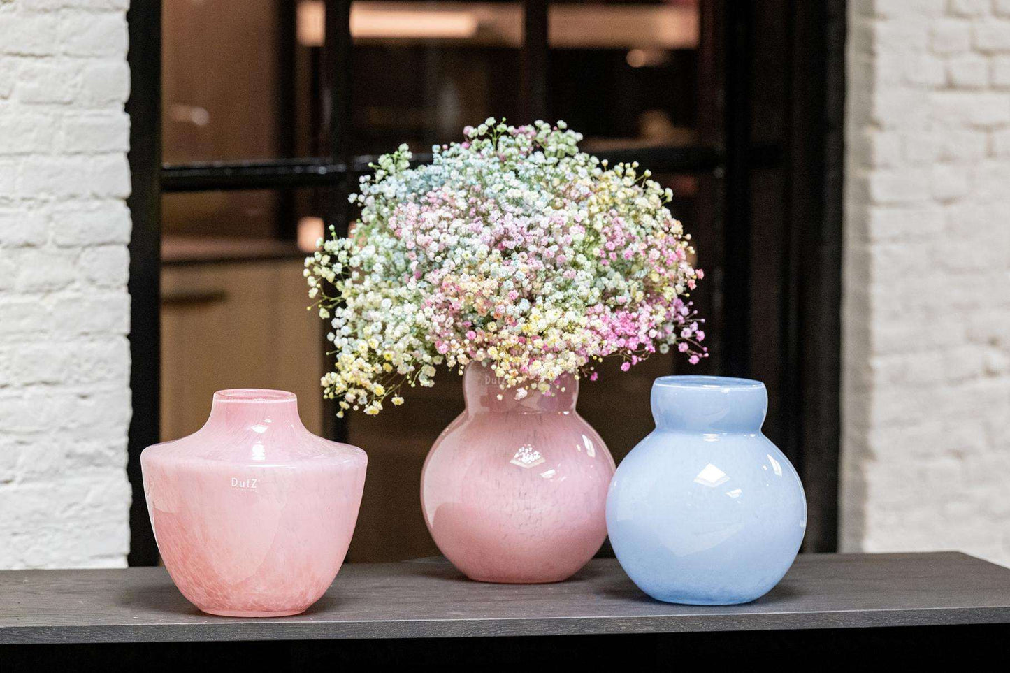 Lowlands Design pink designer vase of glossy ceramic holding gypsophila flowers between pastel pink and blue vases