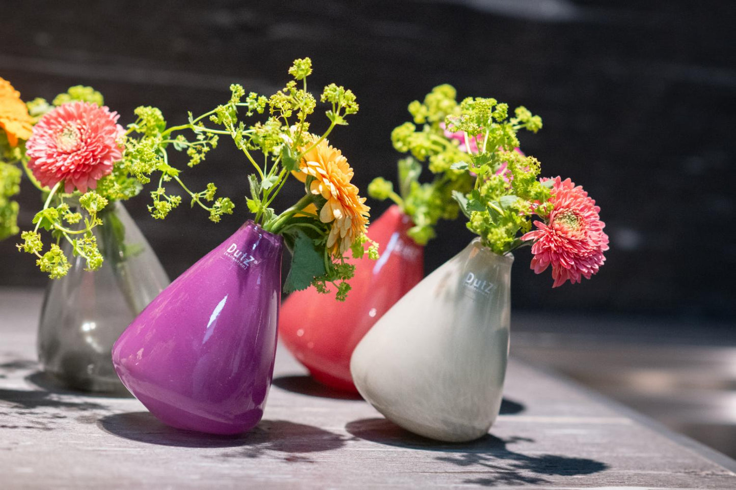 Set of five tumbling vases glass in assorted colours including pink, red, and grey, perfect for fresh flowers