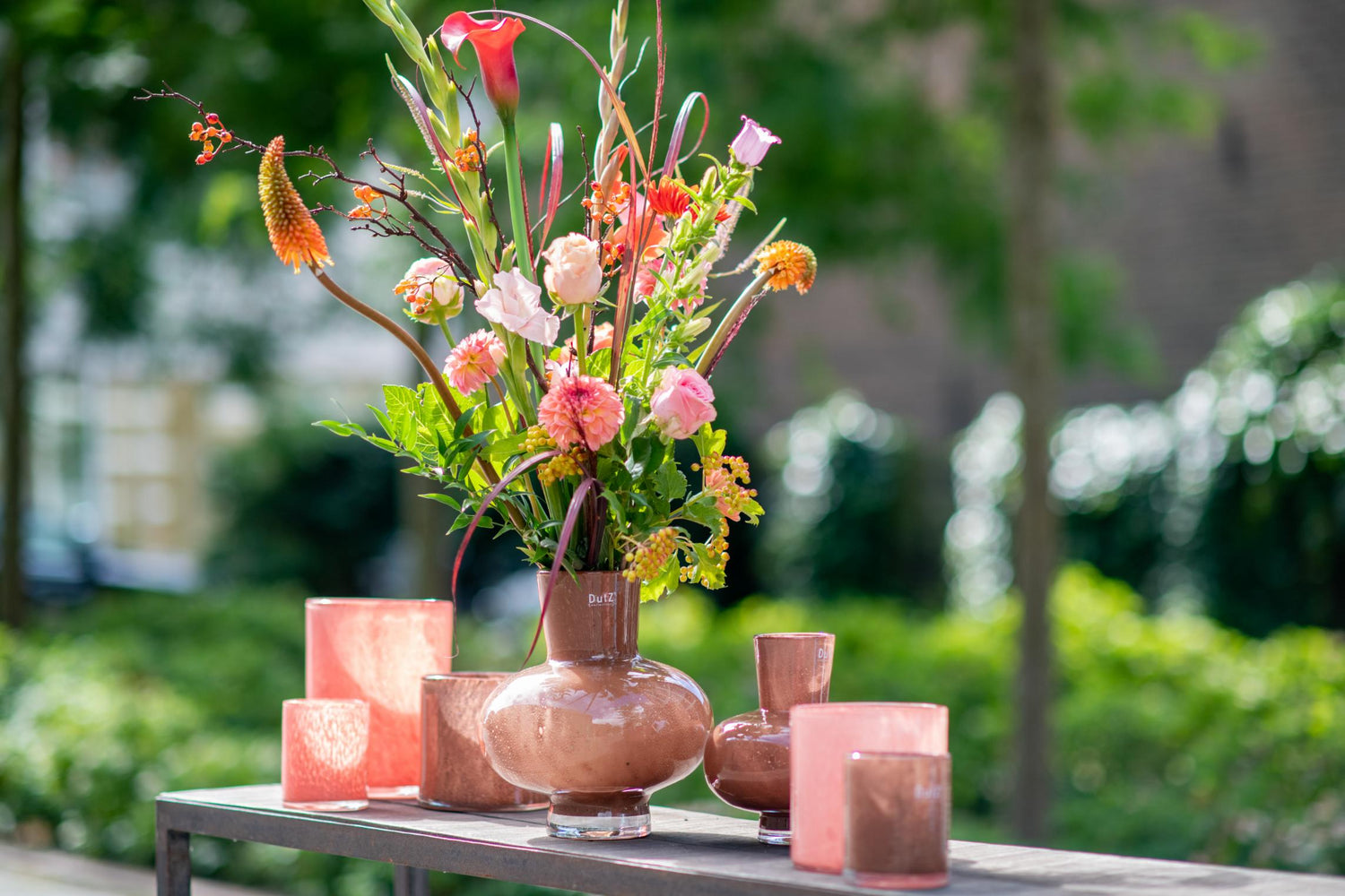 Lowlands Design vase flower bouquet glass with vibrant floral arrangement and decorative candles on a table